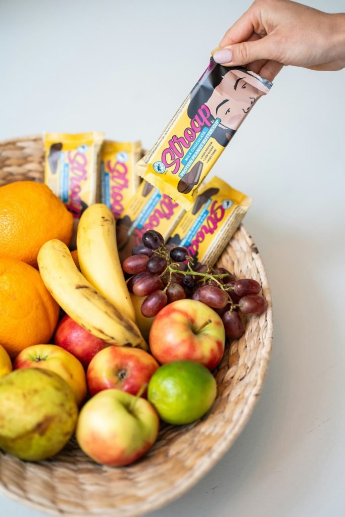 a hand takes a protein snack from a fruit bowl. Stroap Protein snacks are low in carbs as well. Ideal for that snacking moment in between meals. The product in this case is a protein peanut butter cup. Milk chocolate filled with a creamy filling of peanut butter.