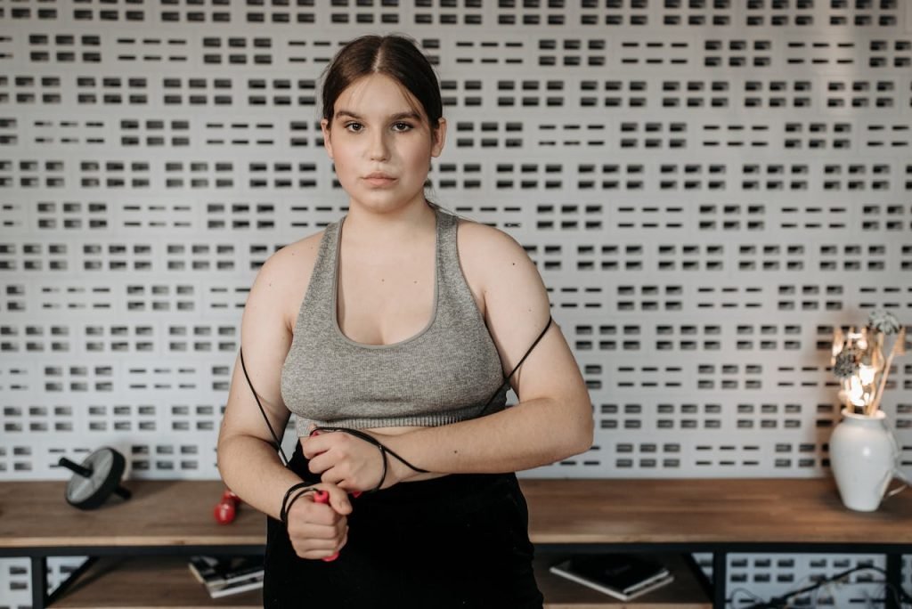 Focused young woman holding a jump rope in a modern indoor gym setting.