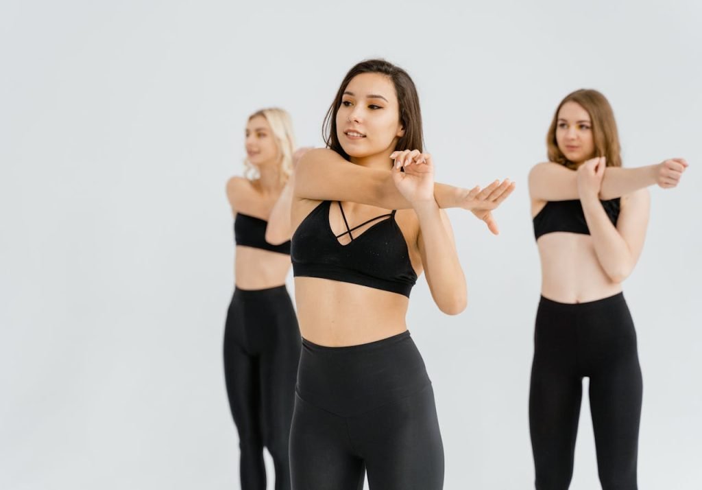 A group of women exercising indoors, focusing on stretching and flexibility routines in a studio.